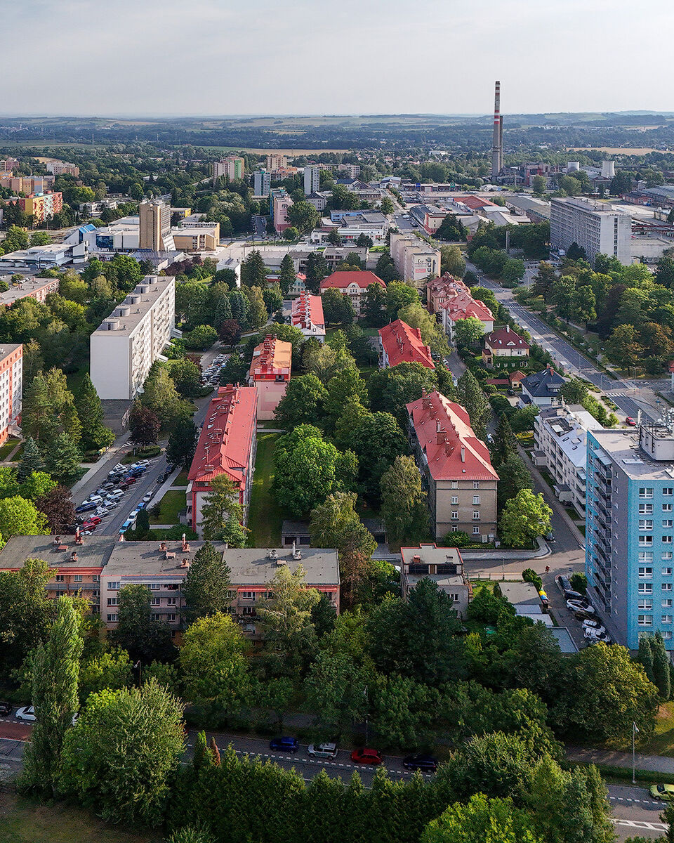 Letecký pohled na Kopřivnici — bytové domy, zeleň a v pozadí tovární komín